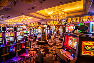 Rows of illuminated slot machines with chairs on a patterned carpet in a casino