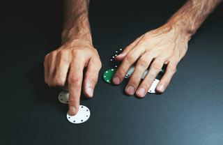 Hands arranging poker chips on a dark surface