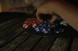 Hand grabbing blue and red poker chips on a table